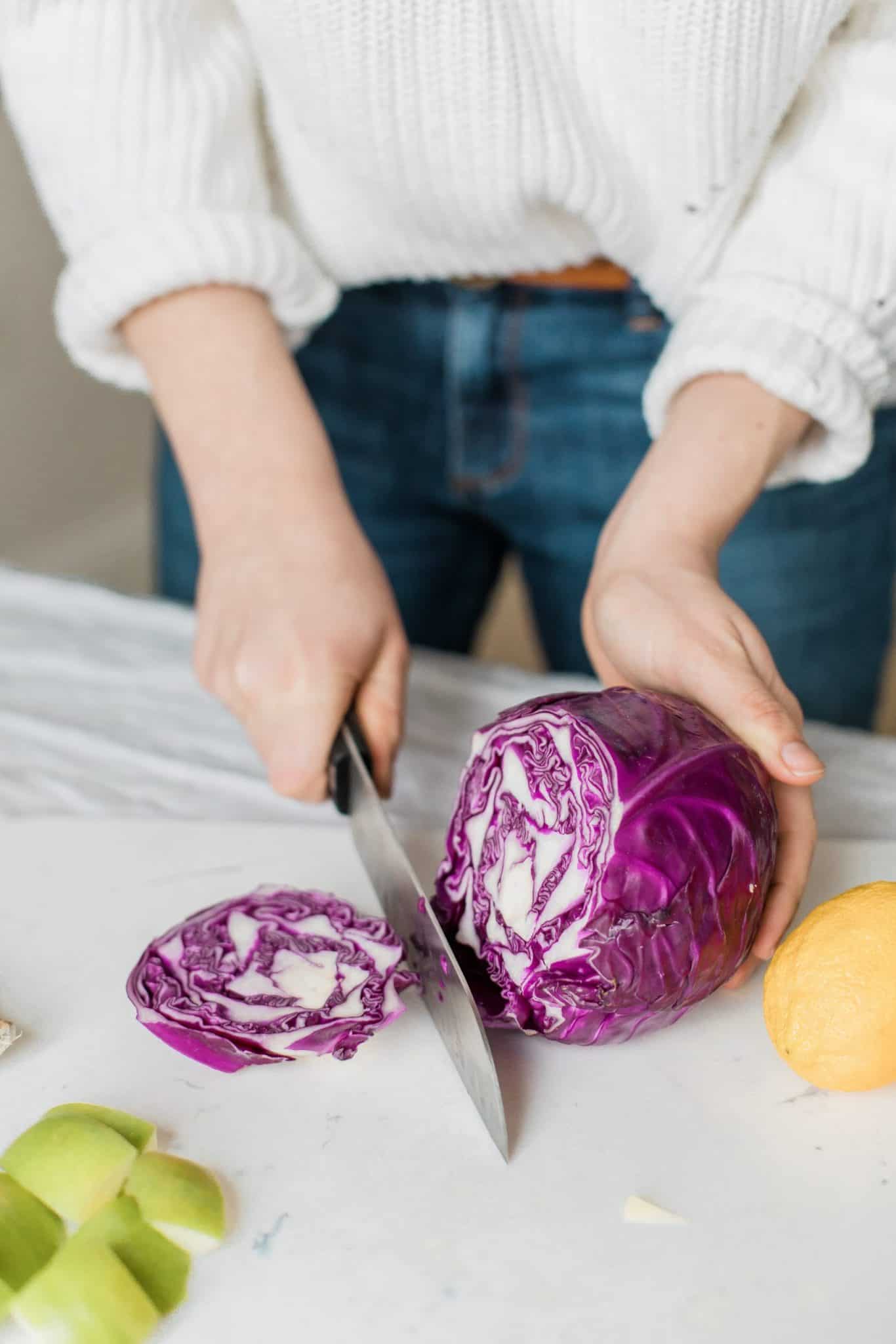 woman chopping purple cabbage with chef knife to develop heart healthy eating habits.
