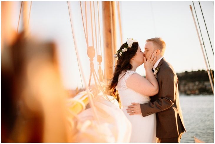 bride and groom kiss on sailboat in sunset center for wooden boats wedding seattle