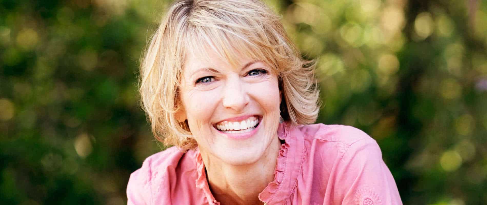 Elizabeth Hunter Diamond gives clairvoyant reading & energy healing, in pink shirt outside in nature.