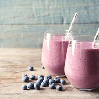 Blueberry pineapple smoothie in stemless glasses with striped paper straws