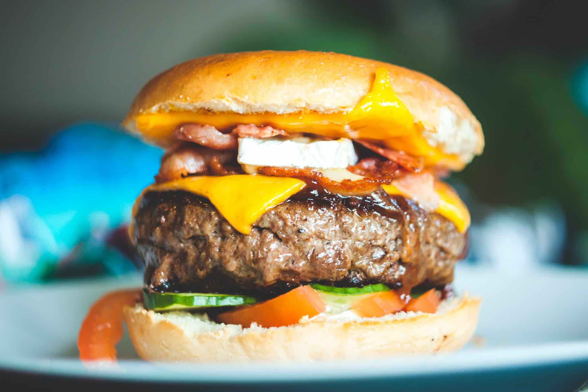 Comparison Burger with cheese and veggies on a bun
