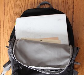 Backpack laying open with binder and papers tucked neatly inside.