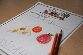 Photo of a portfolio page for parent teacher conferences. Child drew food following a prompt about what he was thankful for.