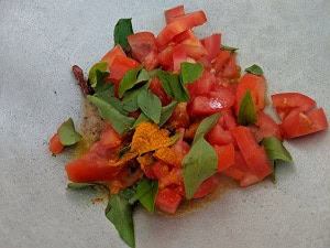 Tomatoes, curry leaves and turmeric powder for lemon rasam