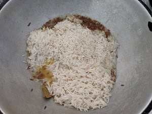 Adding the soaked basmati rice to the whole spices and jeera