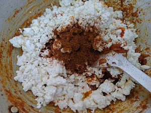 Adding the crumbled paneer to the onion tomato mix with garam masala