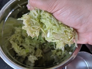 Squeezing out excess moisture from grated dudhi for making muthiya