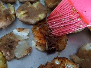 applying herbs mixed with olive oil over the boiled potatoes
