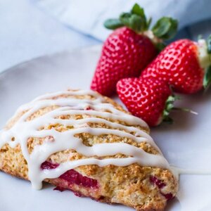 One scone on a plate drizzled with glazing.