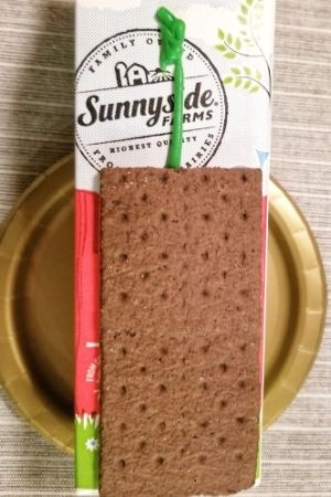 Using frosting to glue chocolate graham crackers to the milk carton to build haunted graham cracker houses.