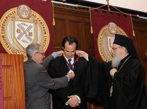 Fordham Provost Stephen Freedman, along with Archbishop Demetrios, present Professor Aristotle Papanikolaou with a ceremonial medal commemorating his installation.
