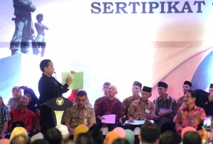 Presiden Jokowi menunjukkan sertifikat saat penyerahan 5000 sertifikat tanah untuk warga Provinsi DKI Jakarta. di Taman Cakung, Jakarta, Senin (3/12) sore. (Foto: Rahmat/Humas)