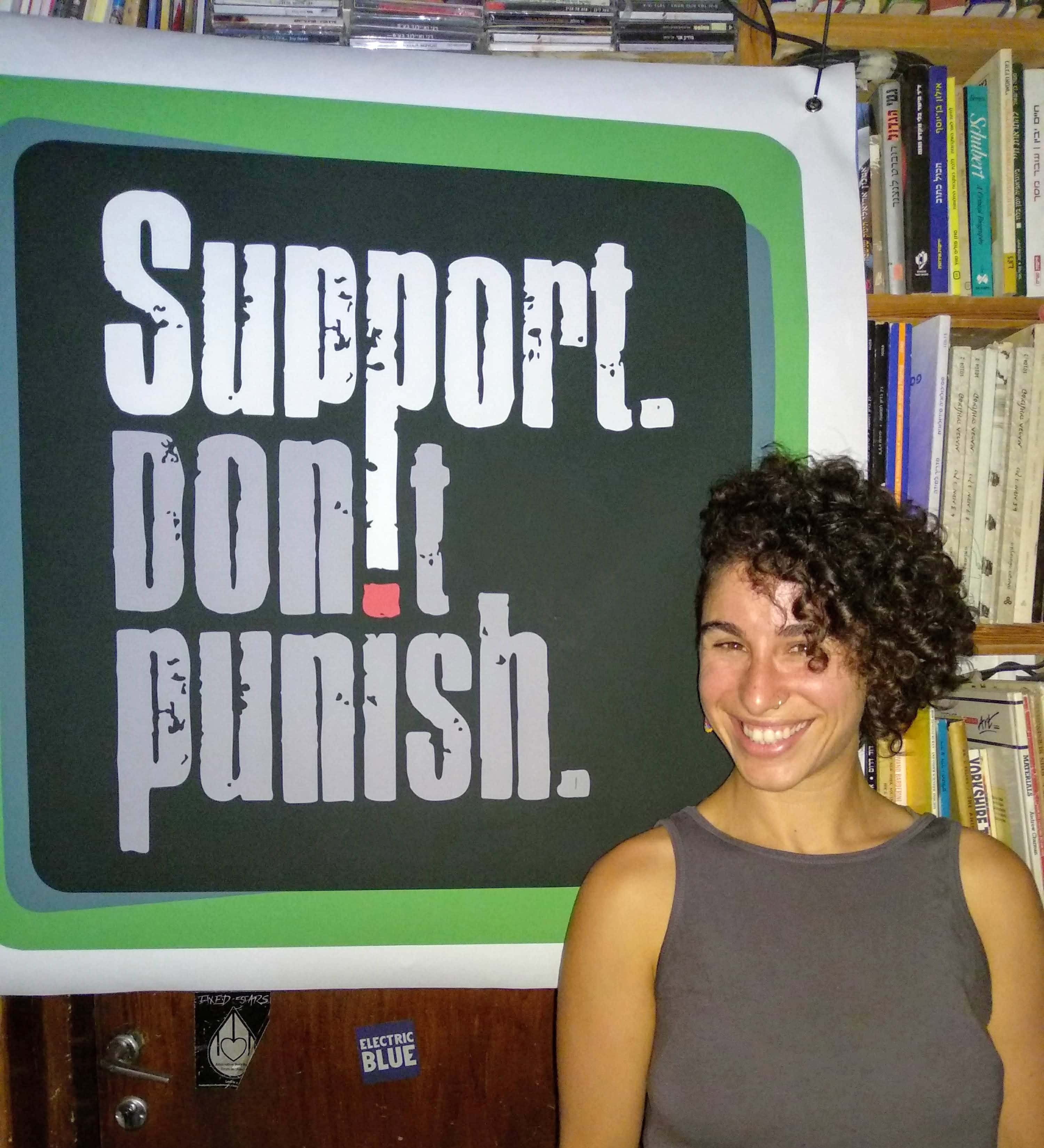 Dovrat from SSDP Israel standing in front of a Support Don't Punish poster.