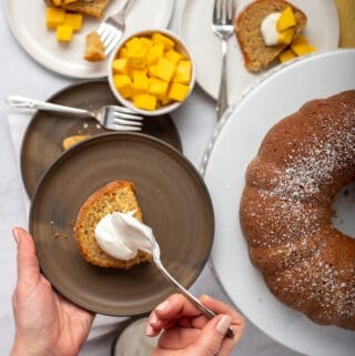 Slice of mango cake with dollop of yogurt and bundt cake in background
