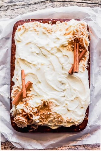 overhead shot of a pumpkin sheet cake with cream cheese frosting decorated with cinnamon and toffee bits