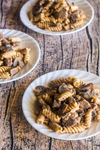 three plates of beef stroganoff with mushrooms served with rotini
