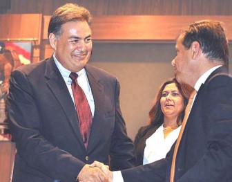 During happier times in 2013, Santa Ana City Manager David Cavazos shakes hands with Mayor Miguel Pulido while Councilwoman Michele Martinez looks on.