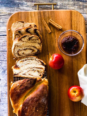 overhead shot of many slices of babka with loaf and apple butter and apples on tray