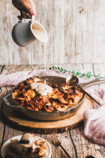brown butter bourbon sauce being poured onto bread pudding in cast iron skillet