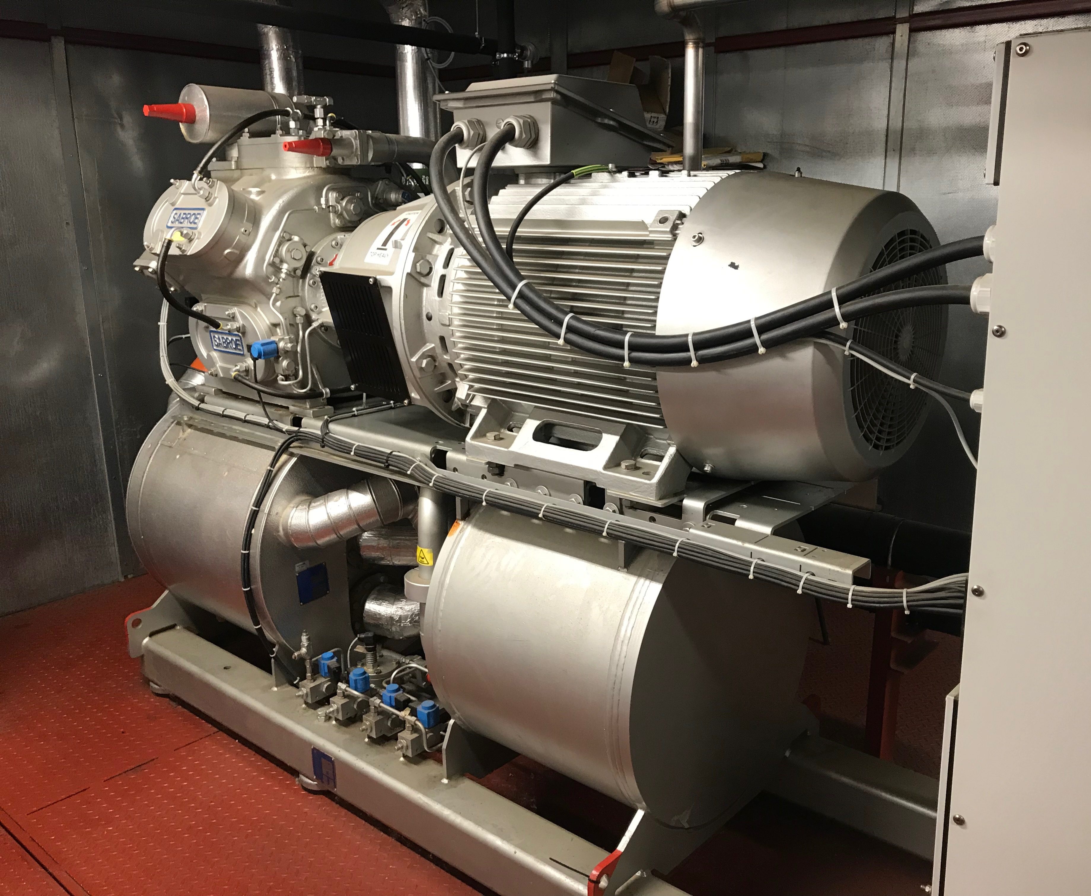 A silver industrial refrigeration plant with compressor cables connected to starter panel
