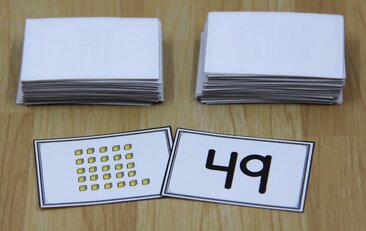 Photo of two game cards for a math war game. One card shows 26 "ones" cubes; the other shows the number 49.