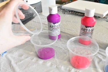pouring water into tempera paint to mix pouring paint