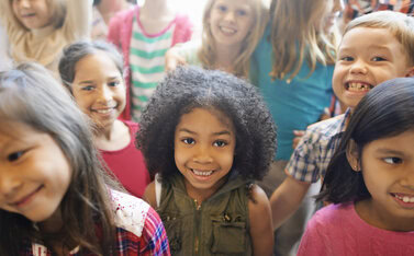 Photo shows a group of smiling children looking at the camera.