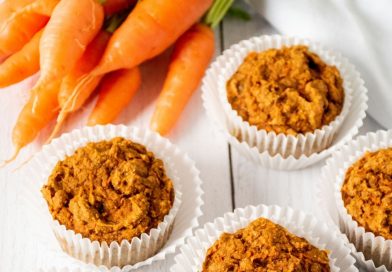 5 muffins on a table with fresh carrots.