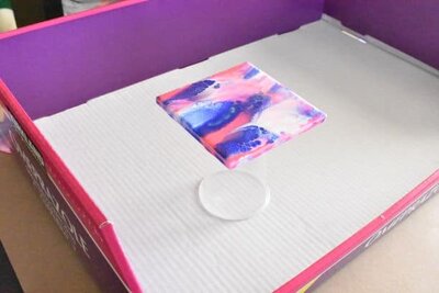 tile raised on plastic cup in cardboard box