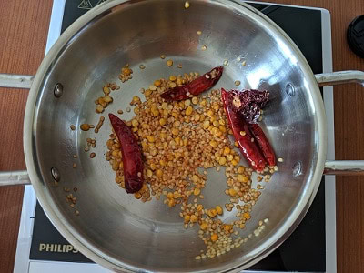Sauteing the lentils and red chillies in sesame oil for coconut thogayal