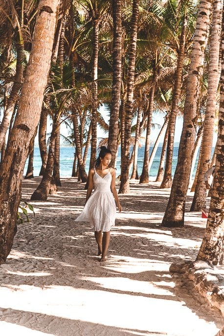 Siargao Island Travel Guide for Non Surfers 8 P A girl in a white dress walks through the palm trees at Cloud Nine, Siargao