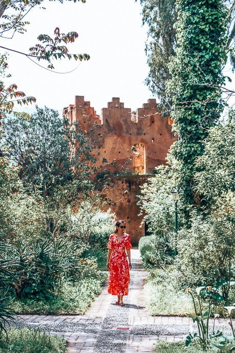 The Perfect Itinerary For 2 Days In Chefchaouen 7 P A woman in a red dress stands in the garden of the kasbah, Chefchaouen Morocco