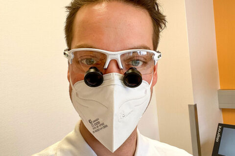HNO-Arzt OA Dr. Philipp Wimmer mit einer Lupenbrille in seiner HNO-Ordination in 1100 Wien, direkt neben der Therme Wien