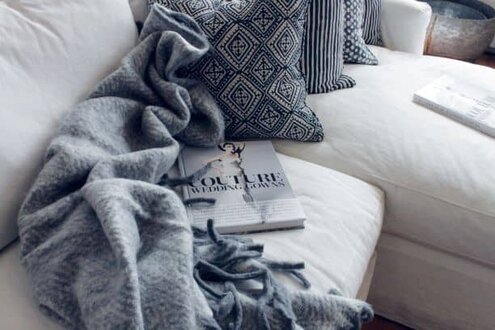 Blanket and pillows on couch with magazine