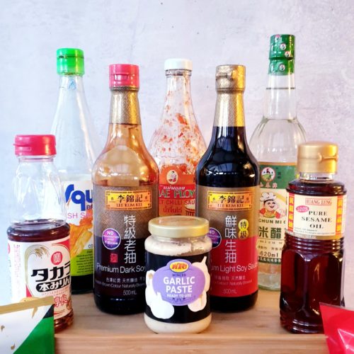 Front on shot of bottles Asian Ingredients including two types of soy, sweet chilli sauce, garlic paste, fish sauce and sesame oil.