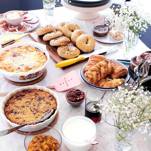 Angled shot of a brunch buffet table showing the food ready to be served. Egg casserole show to the top left.