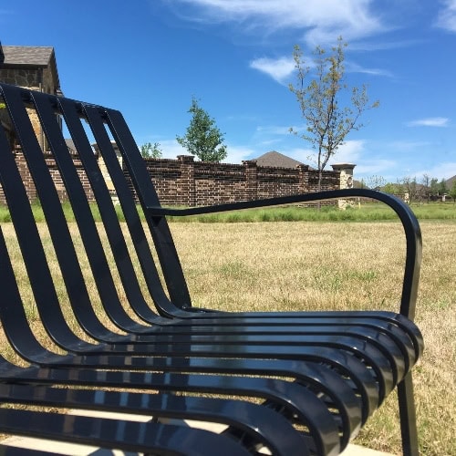 metal bench in grass in front of brick home