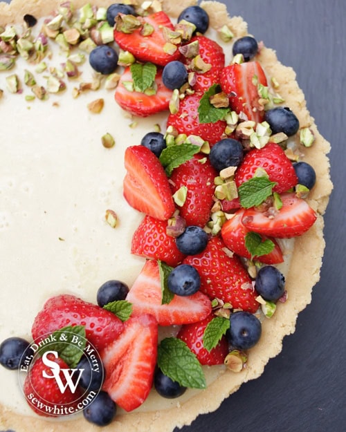 white chocolate tart deocrated with strawberries and blueberries plus pistachios