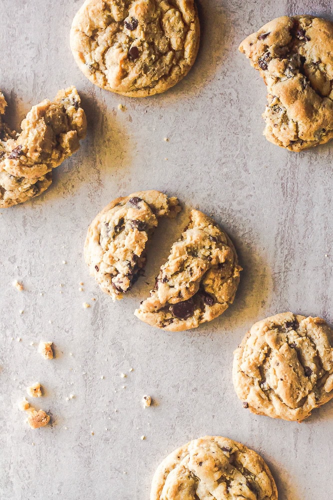 overhead shot of chocolate chip cookies with a few broken in pieces on marble
