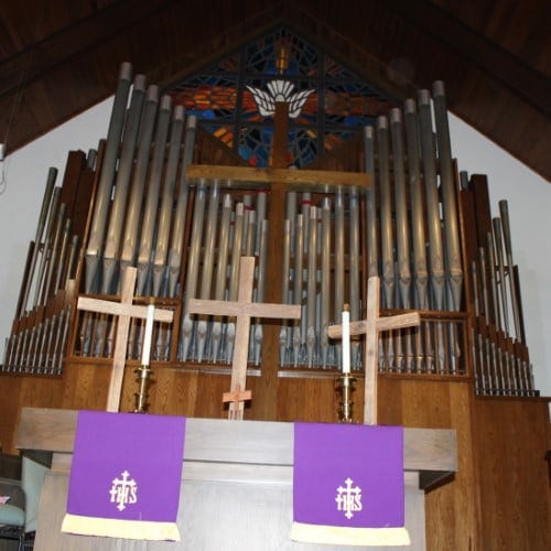 altar with 3 crosses in front of organ case