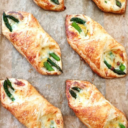overhead of 4 cooked asparagus wraps on their baking tray after cooking shown at an angle