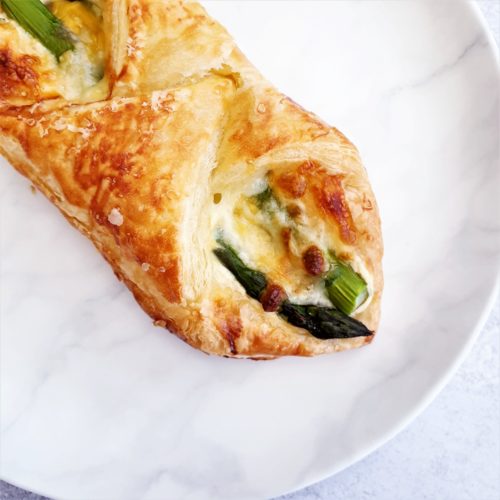 One puff pastry wrap shown from over head on e white plate. This is a close up of half the pastry.