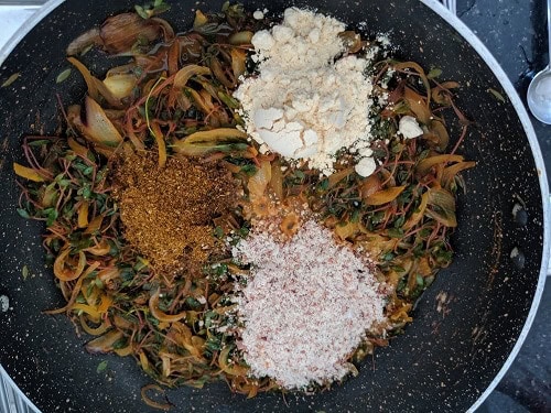 Adding spices and goda masala to chival bhaji