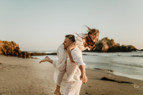 young couple dressed in white eloping on the beach