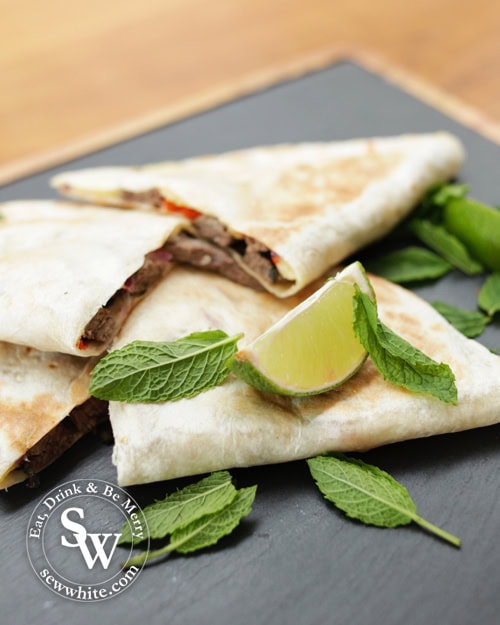 Mojito Beef Quesadillas on a slate board with fresh lime and mint