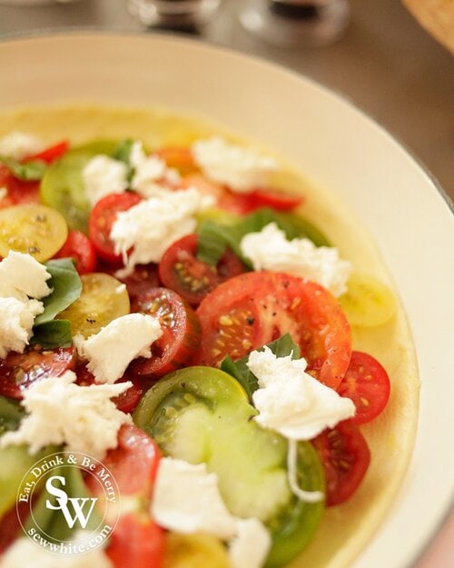 A close up of tiger tomatoes, green tomatoes, yellow tomatoes topped with mozzarella ready for the oven.
