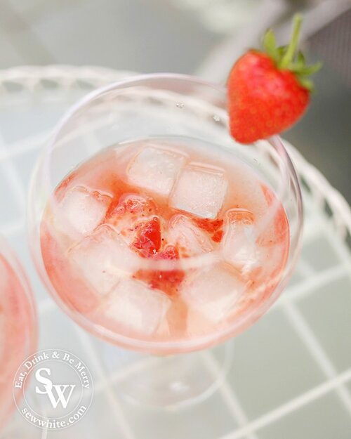 A close up of the gin balloon glass with ice and the strawberry jam and gin mixture waiting to be topped up with tonic water.