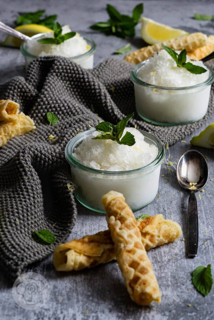 Eiskaltes Zitronen-Minz-Granita 4 3 Gläser Zitronen Granita mit Zitronenvierteln, Minze und Waffeln