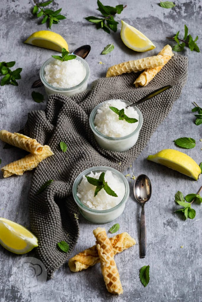 Eiskaltes Zitronen-Minz-Granita 2 3 Gläser Zitronen Granita mit Zitronenvierteln, Minze und Waffeln