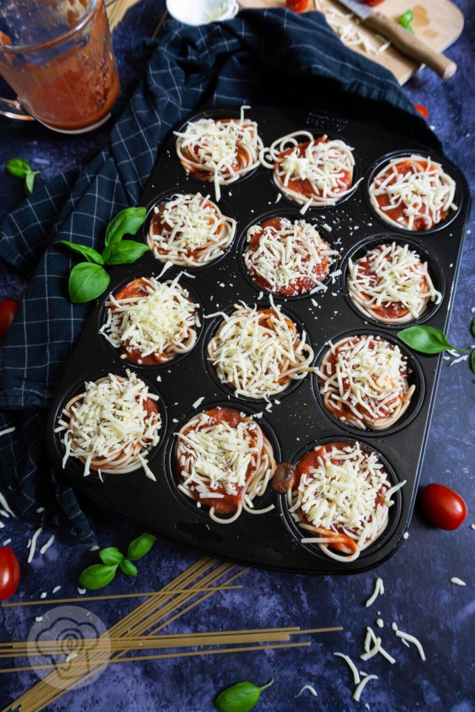 Einfache Spaghetti Muffins 3 Spaghetti Muffins im Muffinblech mit Käse bestreut, ungebacken